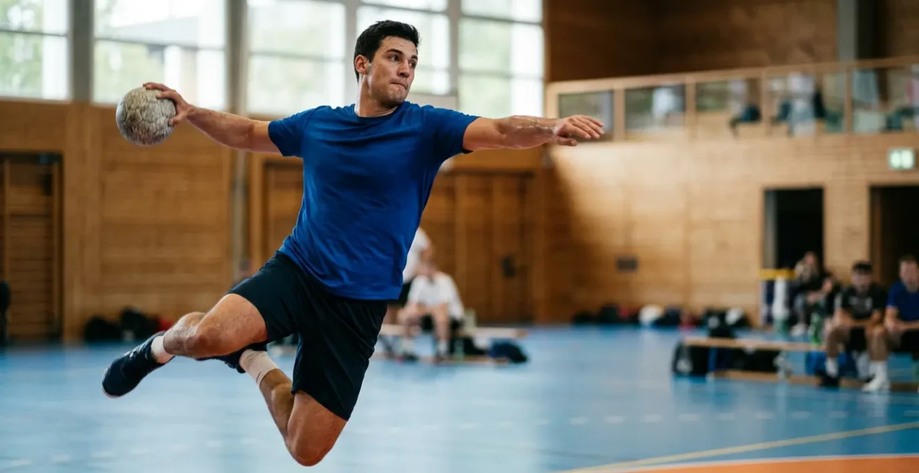 Joueur de handball en pleine action de tir, montrant la puissance musculaire et l'explosivité
